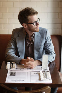 Thoughtful man looking away while sitting at table in restaurant