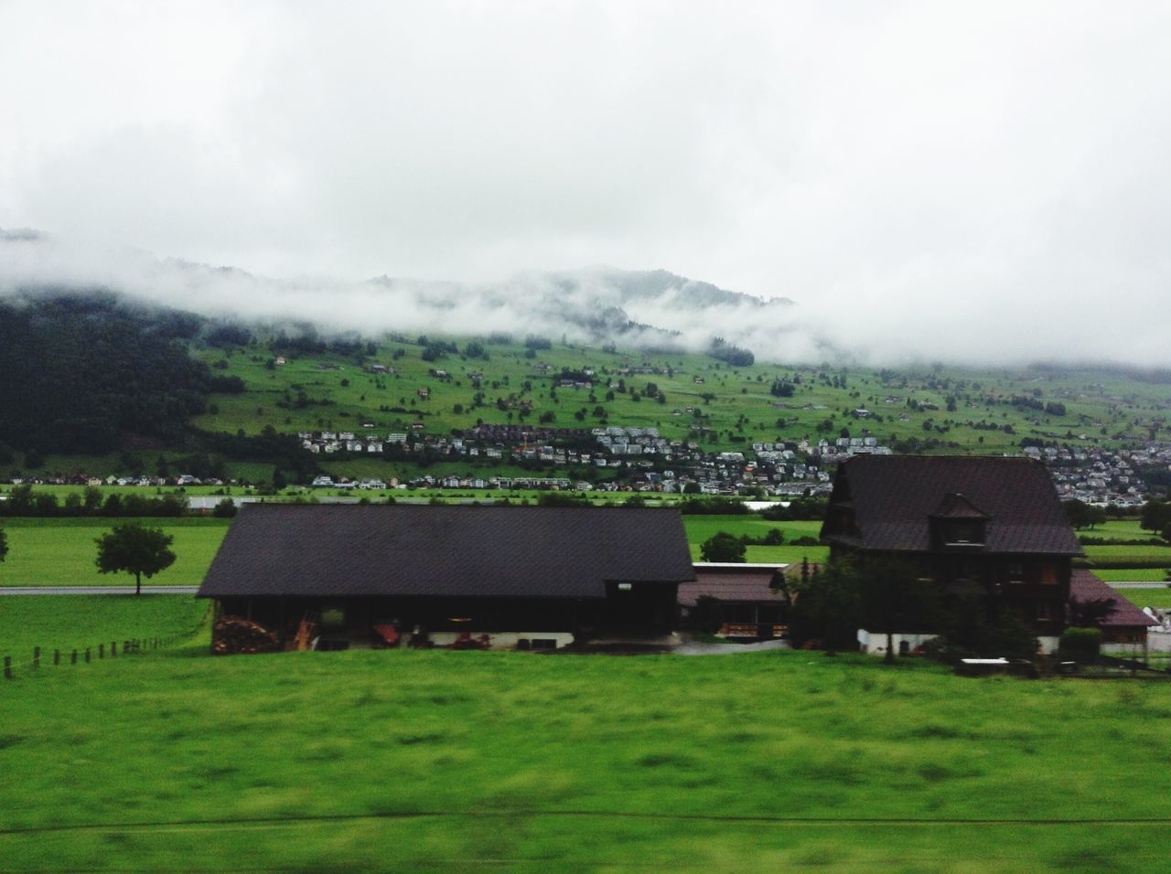 landscape, grass, field, building exterior, sky, built structure, architecture, mountain, scenics, house, tranquility, tranquil scene, green color, weather, nature, beauty in nature, grassy, cloud - sky, rural scene, tree