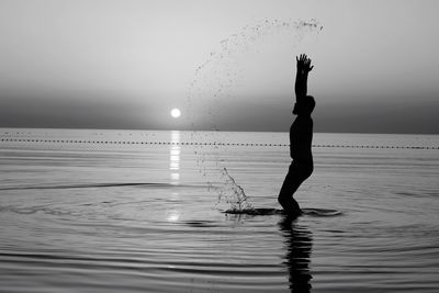 Silhouette woman standing on beach against clear sky