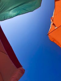 Low angle view of flags against clear blue sky