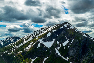 Scenic view of snow covered mountains against cloudy sky