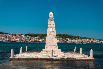 View of historic building by sea against clear blue sky