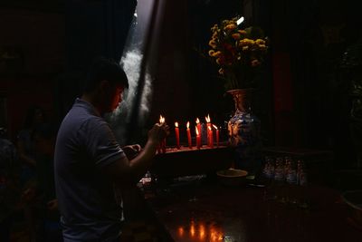 Man igniting candle in darkroom