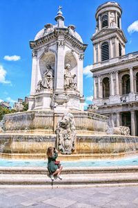 Woman leaning on historic building against sky