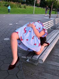 Girl leaning on bench at footpath