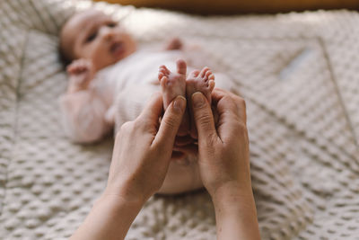 Mum making baby massage, mother massaging infant bare foot, preventive massage for newborn.