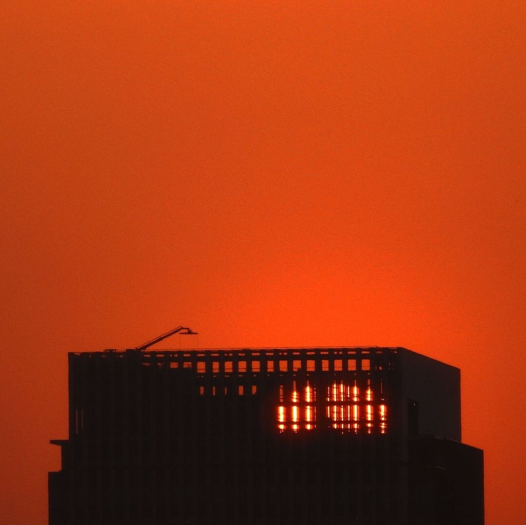 LOW ANGLE VIEW OF ILLUMINATED BUILDING AGAINST ORANGE SKY