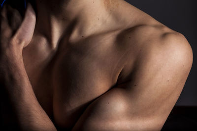 Close-up of shirtless man against black background