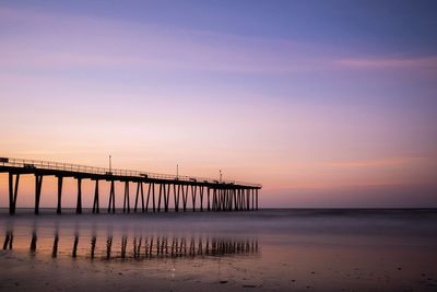 Pier over sea against sky during sunset
