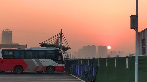 Vehicles on road against orange sky