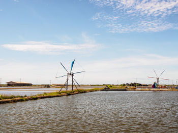 Traditional windmill by river against sky