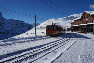 Snow covered railroad tracks by mountain against sky