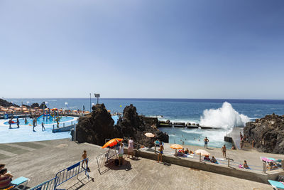 People on beach against clear blue sky