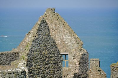 Old building by sea against blue sky