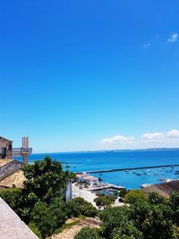 Scenic view of sea by buildings against blue sky