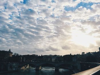 Bridge over river against cloudy sky