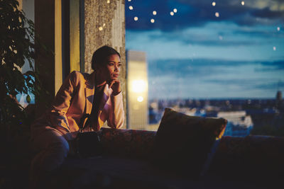 Young woman looking away while sitting at home