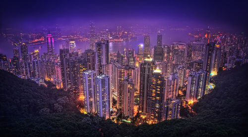 Illuminated cityscape against sky at night