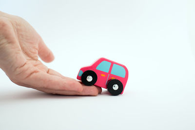 Close-up of hand holding toy car over white background