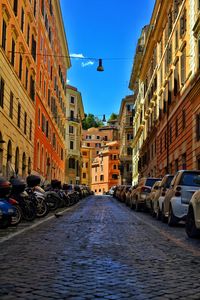 Cars on street in city against blue sky