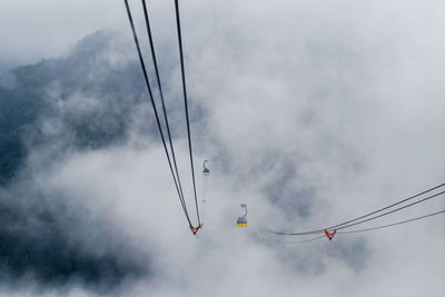 Low angle view of overhead cable cars against sky