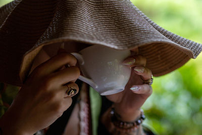 Close-up of woman wearing hat and drinking tea