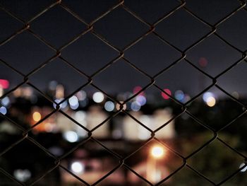 Full frame shot of chainlink fence against sky at night