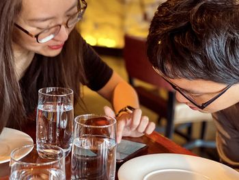 Close-up of asian man and woman in eyeglasses having a discussion over lunch in a restaurant.