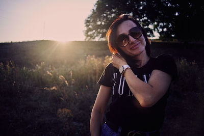 Young woman wearing sunglasses standing on field