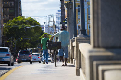 Rear view of people walking on road along buildings