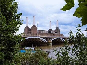 Arch bridge over river by building against sky