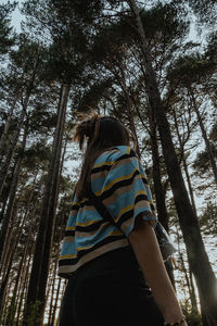 Rear view of woman standing amidst trees in forest