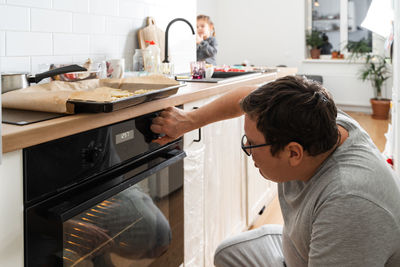 Close up view of the male person in apron standing in front of the open oven 