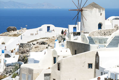 Houses and windmill in oia at santorini against sea