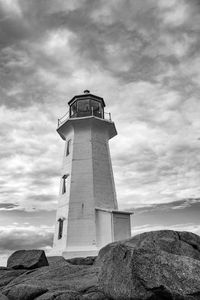 Lighthouse on beach against cloudy sky