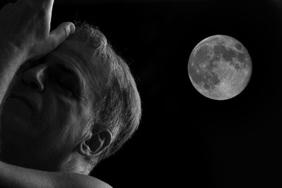 Low angle view of mature man against moon in sky at night