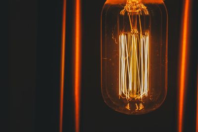 Close-up of illuminated light bulb against black background