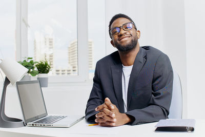 Portrait of businessman using laptop at office