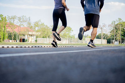 Low section of friends running on road