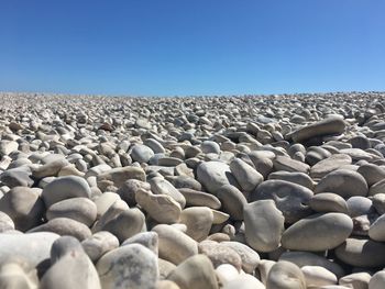 Surface level of pebble beach against clear sky