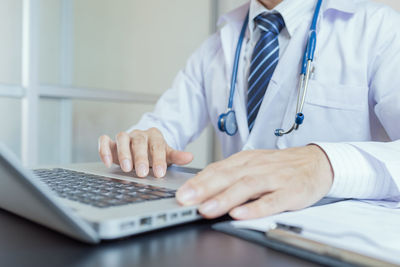 Midsection of man using laptop on table