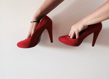Close-up of hands holding high heels over white background