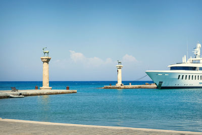 Seascape view on deer statues and ship at the enrance to the mandraki harbour, rhodes