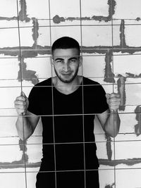 Portrait of young man standing against wall