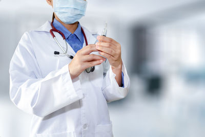 Midsection of female doctor holding syringe