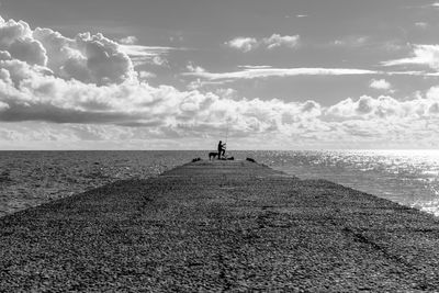 Pier on sea against cloudy sky