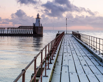 Pier on sea against sky during sunset