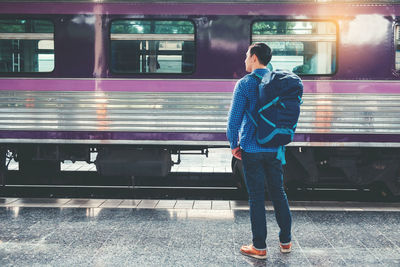 Man standing by train at railroad station platform