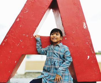 Portrait of smiling boy standing against red wall