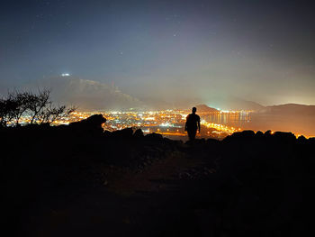 Rear view of silhouette people on beach against sky at night